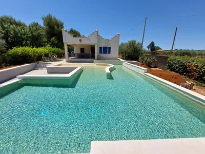 Piscina turchese vista frontale con villa siciliana